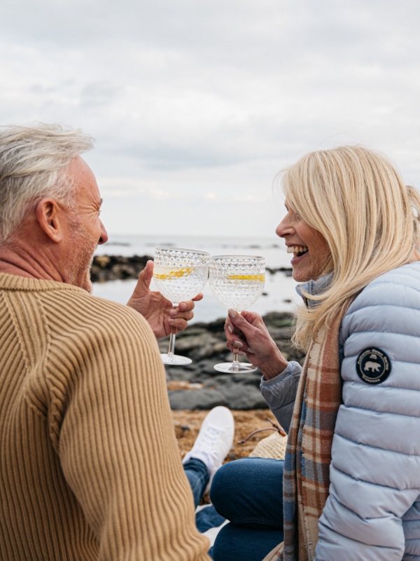 a smiling couple clink glasses of gin